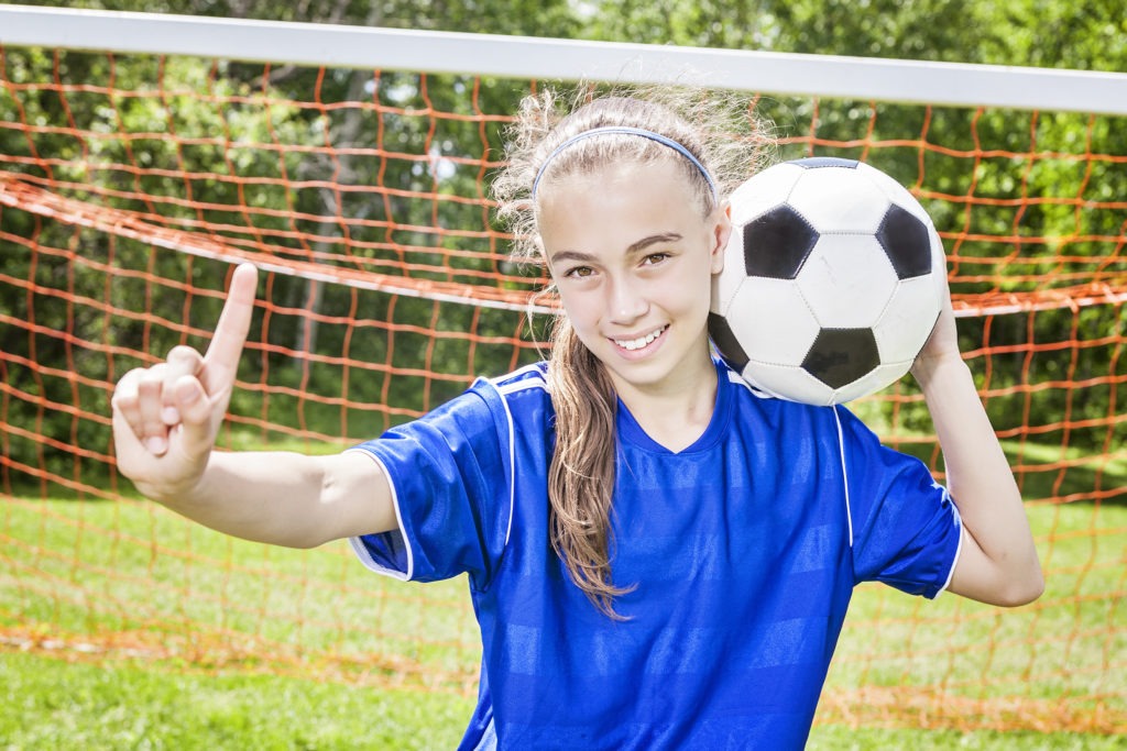Young, smiling girl wearing braces and playing soccer