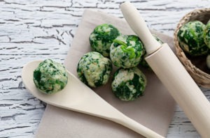 spinach balls with a wooden spoon and rolling pin