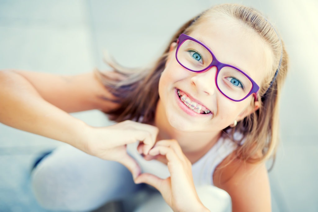 girl with braces holding up heart
